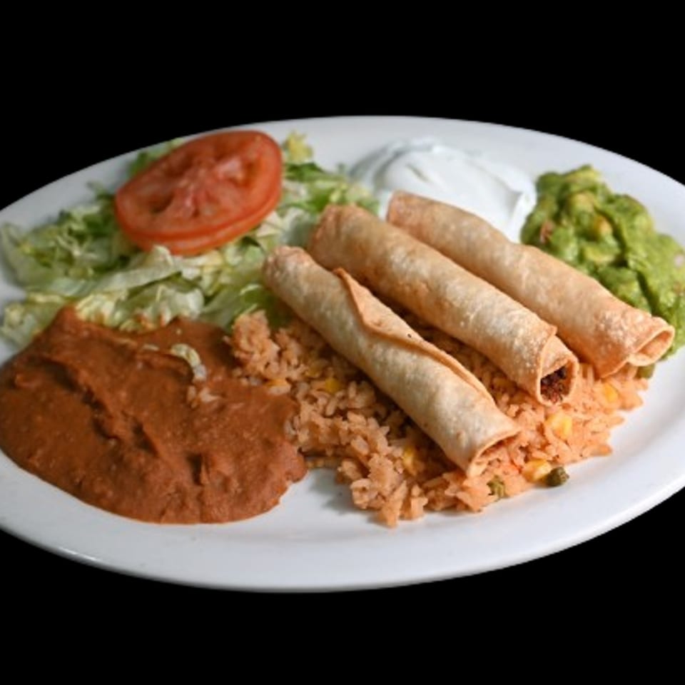 A plate of Taqueria Jalisco's taquitos with rice, refried beans, lettuce, tomato, sour cream, and guacamole.