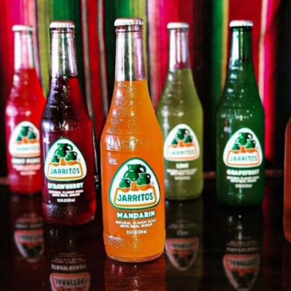 Assortment of Jarritos sodas in various fruit flavors, including mandarin, strawberry, lime, and grapefruit.